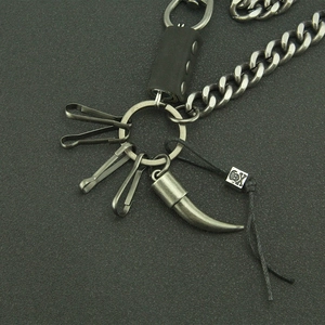Detail of punk silver chain with skull bead, black rivet tube and horn pendant