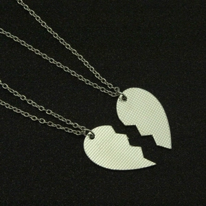 Detail of two-piece interlocking heart pendants with matte silver textured finish