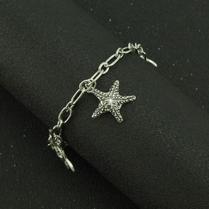 Silver marine chain bracelet featuring a textured starfish pendant on a black surface