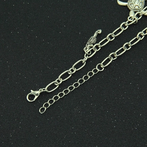 Detail of silver turtle and seahorse charms on a metal chain with lobster clasp
