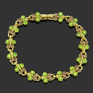 Golden flower link bracelet with green and purple rhinestones on a black background
