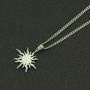 Detailed close-up of polished silver sun pendant on a Cuban link chain necklace