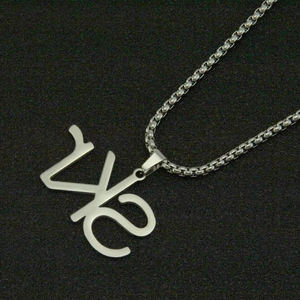 Close-up of a silver WS letter pendant on a box chain over a black textured surface