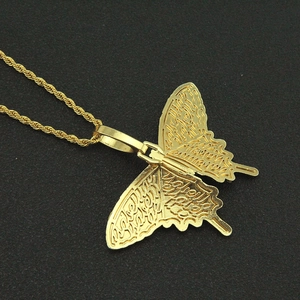 Macro view of gold butterfly pendant with intricate engraved wings on a twist chain
