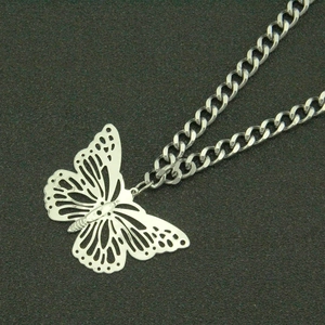 Detailed close-up of punk style hollow butterfly pendant on a thick silver curb link chain