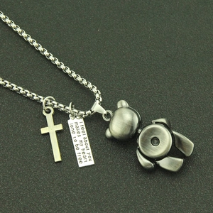 Detail of vintage teddy bear pendant with cross and engraved tag on box chain