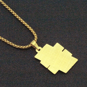 Detailed macro view of the gold tiered geometric pendant with box chain on black texture