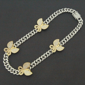 Detail van zilveren Cuban-schakelketting met gouden vlinderhangers en steentjes