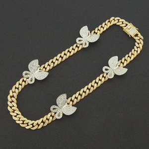 Detail van gouden Cubaanse schakelketting met kristallen vlinders en strass sluiting