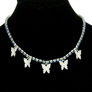 Collier argenté avec cinq pendentifs papillons bleu foncé sur une chaîne de tennis cristal