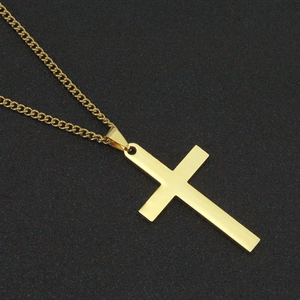 Gros plan d'un pendentif croix en or poli avec chaîne gourmette classique sur noir