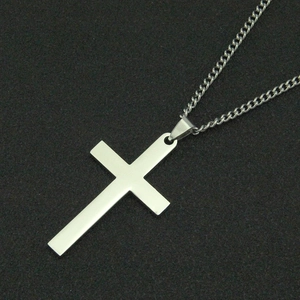 Gros plan d'un pendentif croix en argent poli avec finition miroir et fine chaîne en métal