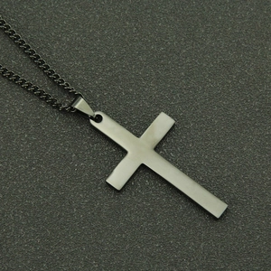 Gros plan sur le pendentif croix en acier noir mat et la chaîne à maillons de style punk