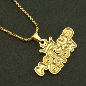 Detailaufnahme eines goldenen Kronen-Anhängers mit World-Schriftzug und Box-Kette