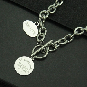 Détail macro du fermoir OT en acier et des pendentifs gravés pour collier hip-hop