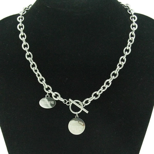 Vue macro d'un collier chaîne épaisse en acier inoxydable avec fermoir OT et breloques