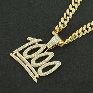 Macro shot of hip hop 100 pendant necklace with pavé cubic zirconia on golden cuban link