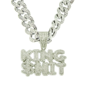 Macro shot of silver hip hop pendant with KING $HIT letters and iced out cuban chain link