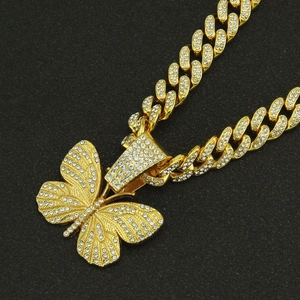 Detailed macro view of gold-plated iced out cuban link chain with diamond butterfly pendant