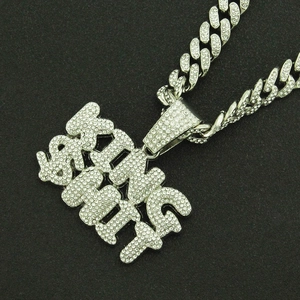Macro view of iced out KING SHIT letter pendant with silver Cuban link chain