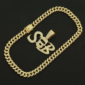 Close-up of hip hop gold Cuban link chain with iced out SB letter pendant details