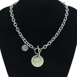 Détail du collier à gros maillons en acier avec fermoir OT et pendentifs gravés