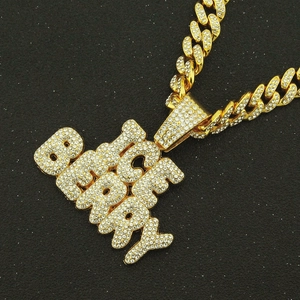 Gros plan du pendentif Rich Berry serti de strass sur une chaîne cubaine dorée élégante