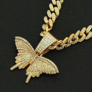 Vue détaillée du pendentif papillon hip-hop avec strass blancs sur chaîne cubaine dorée