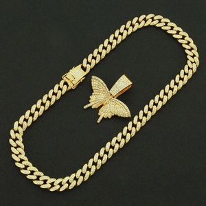 Détail de la chaîne cubaine dorée et du pendentif papillon serti de zircons brillants