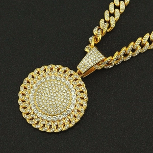 Close-up of gold-plated iced out Cuban link chain and sunflower pendant with white stones