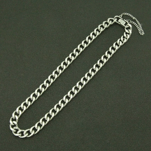 Détail d'un collier à maille gourmette en acier avec fermoir et chaîne de sécurité