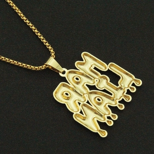 Detail of golden box chain necklace with iced out dripping letter pendant