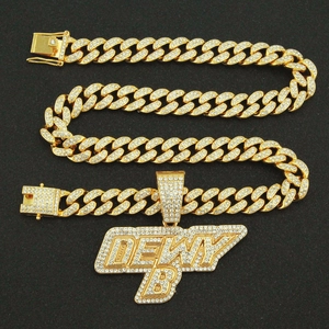 Gros plan sur la chaîne cubaine dorée avec un grand pendentif lettre DEWY B serti