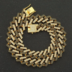 Macro shot of thick gold Cuban chain with black and white pavé setting and secure clasp