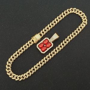 Close-up of gold iced out Cuban link chain with a large ruby pendant for men