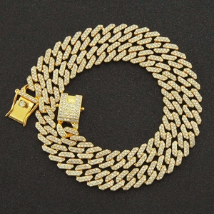 Detailed macro view of gold-tone Cuban link necklace with iced out pavé crystal clasp