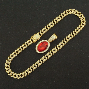 Detailed close-up of a gold Cuban chain with a large oval ruby pendant and crystals