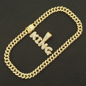 Gros plan sur une chaîne cubaine dorée sertie de strass avec un pendentif KING brillant
