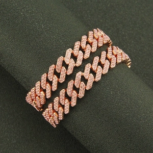 Close-up of rose gold Cuban link chain set with pavé pink rhinestones on textured display