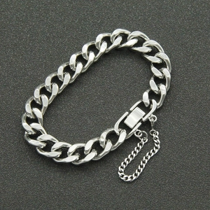Detail of silver curb chain bracelet with folding clasp and safety chain on grey background