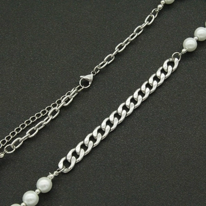 Détail de collier hybride en perles avec chaîne gourmette et fermoir mousqueton gris