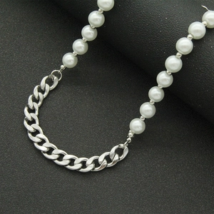 Collier minimaliste en perles et chaîne cubaine argentée sur un présentoir noir texturé