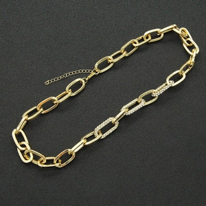 Gold cuban link necklace with crystal-encrusted paperclip links on a black textured background