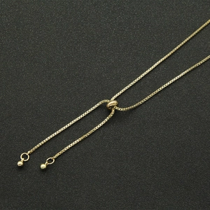 Detail of golden box chain necklace featuring an adjustable slider clasp and polished beads