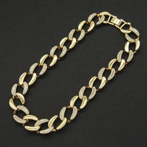 Détail d'un collier à maille gourmette dorée avec pavage de strass étincelants