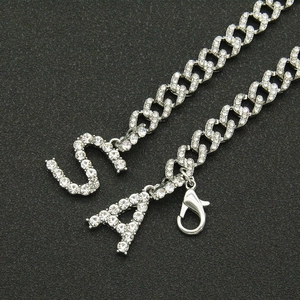 Silver Cuban link necklace with iced out crystal letters S and A on black background