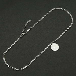 Detail of silver double-layered Cuban chain necklace with a vintage sailboat coin pendant