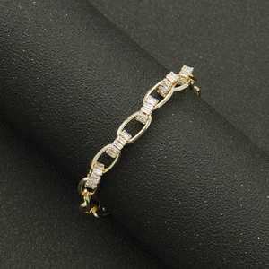 Polished gold link bracelet with baguette-cut zircon insets on a dark display stand