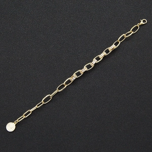 Detail view of gold chain bracelet with rectangle zircon stones and coin pendant charm