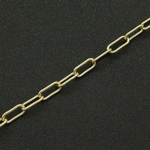 Detail of a golden paperclip chain necklace on a textured black surface